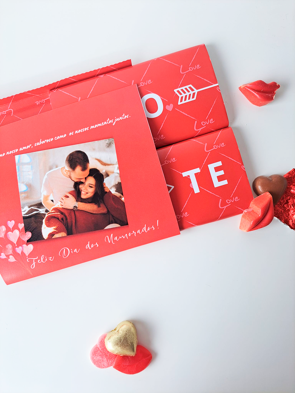 Cartão vermelho com foto de casal e chocolates vermelhos em forma de lábios e coração