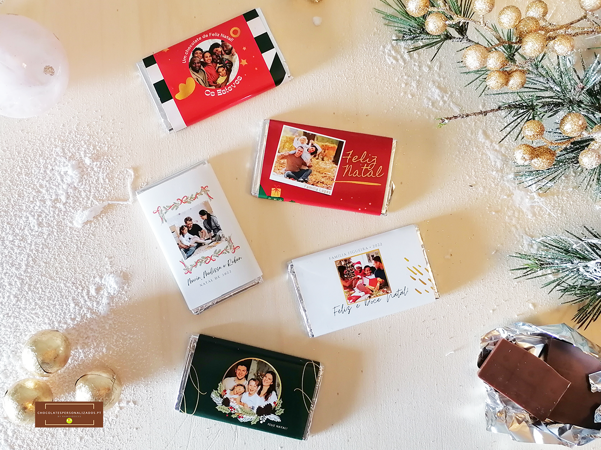 Barras de chocolate com embalagens festivas em vermelho, branco, verde e preto sobre superfície branca com decoração natalina