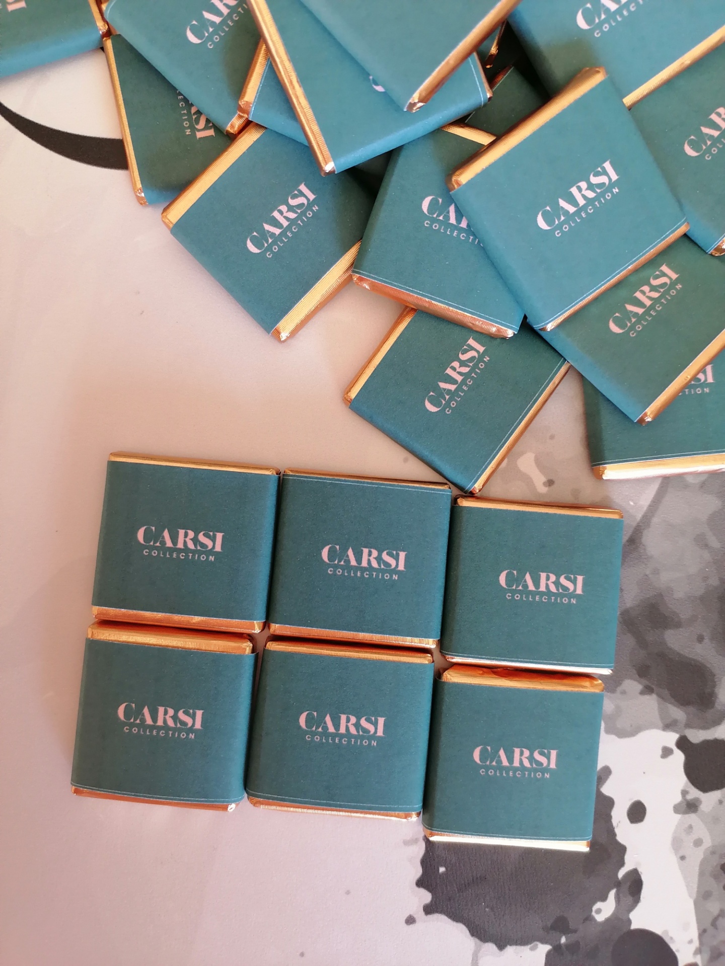 Pacotes pequenos verdes com texto CARSI COLLECTION em superfície clara