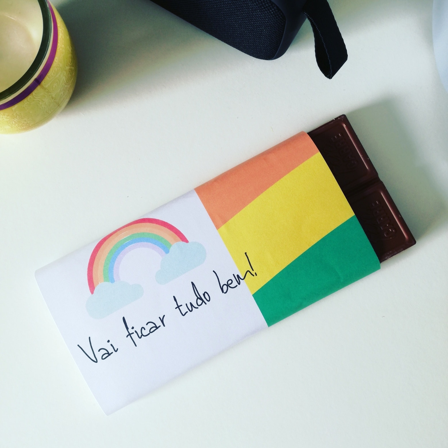 Barra de chocolate embrulhada com arco-íris e mensagem positiva.
