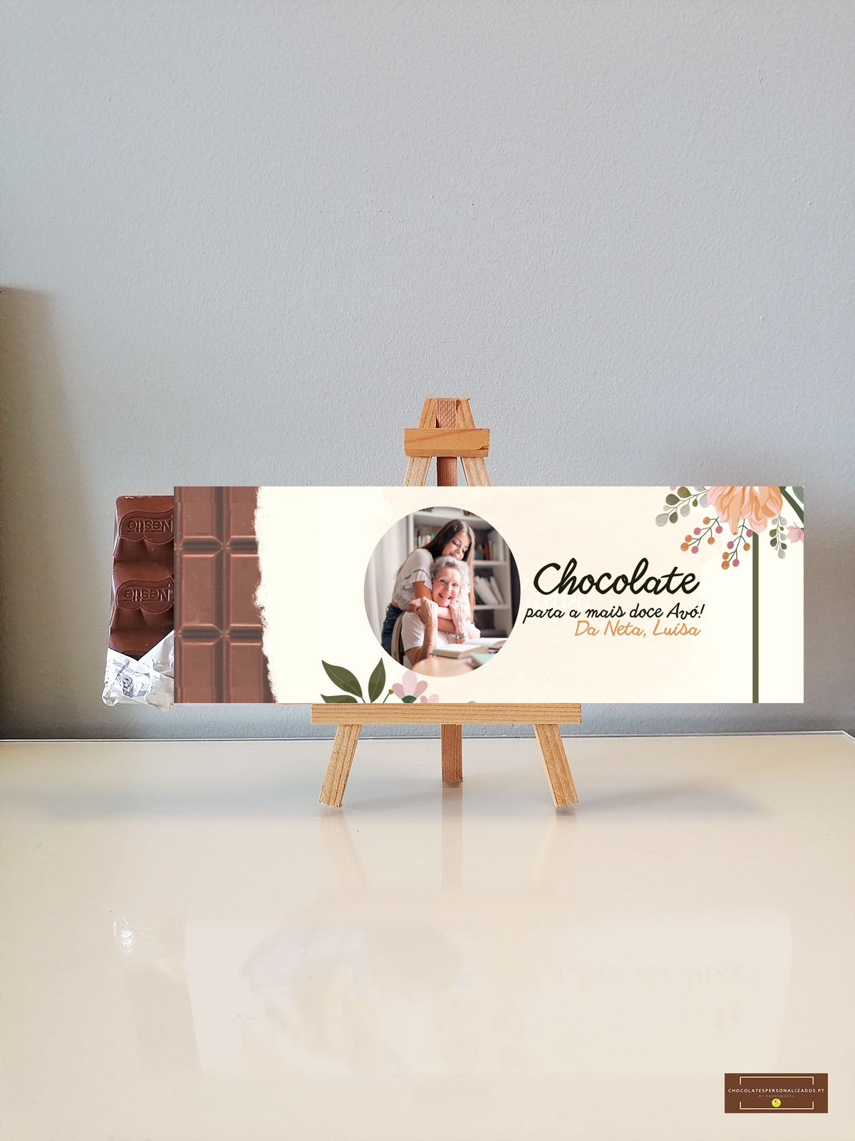 Embalagem de chocolate com texto dedicado e foto em cavalete de madeira sobre superfície branca