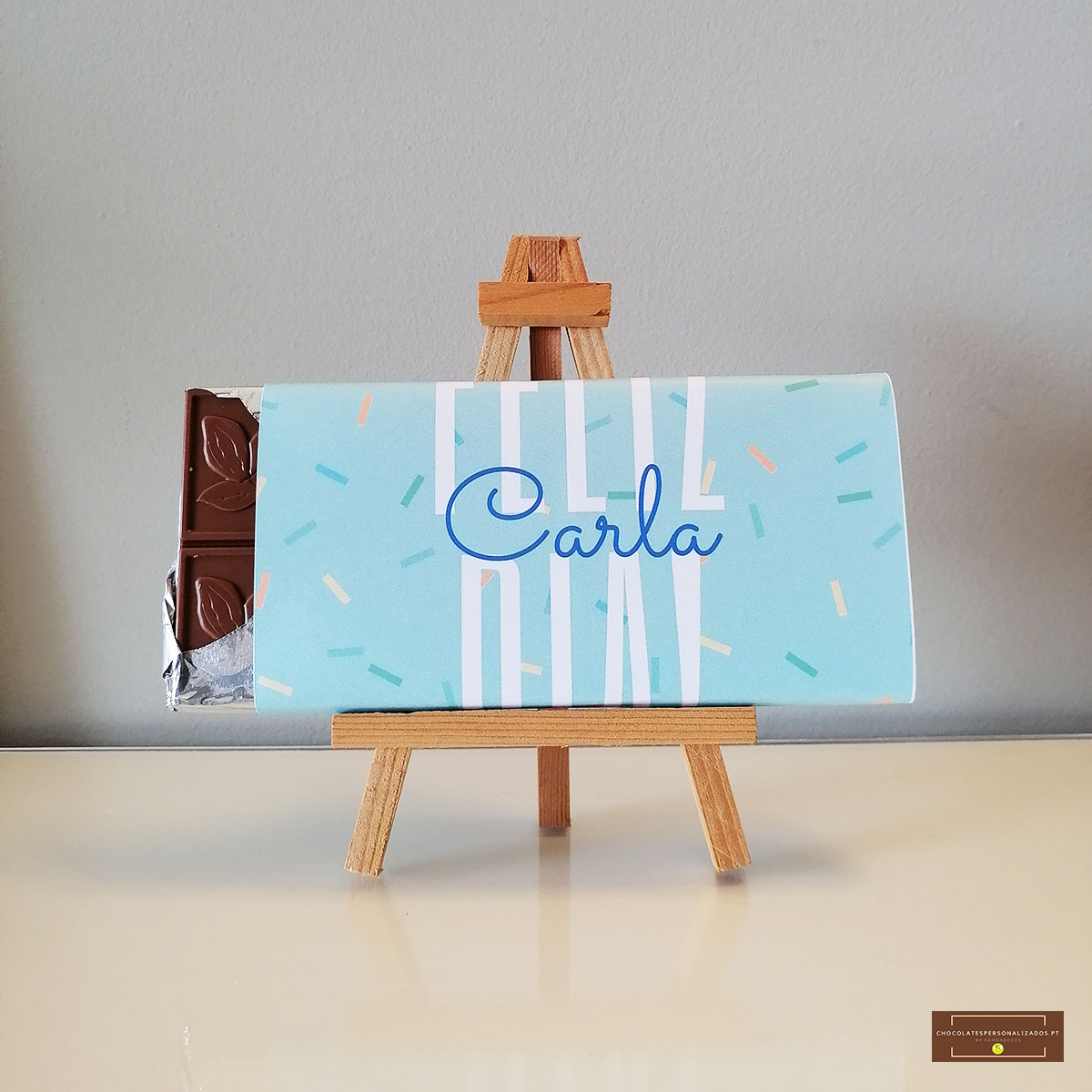 Barra de chocolate com embalagem azul clara em cavalete de madeira