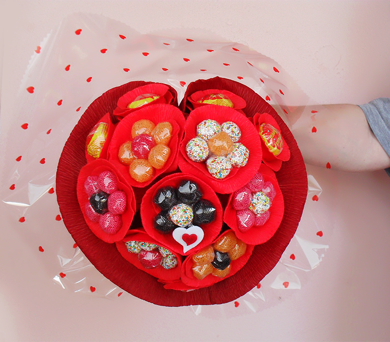 Bouquet de doces coloridos e chocolates em forma de coração, embalado com papel celofane com corações vermelhos