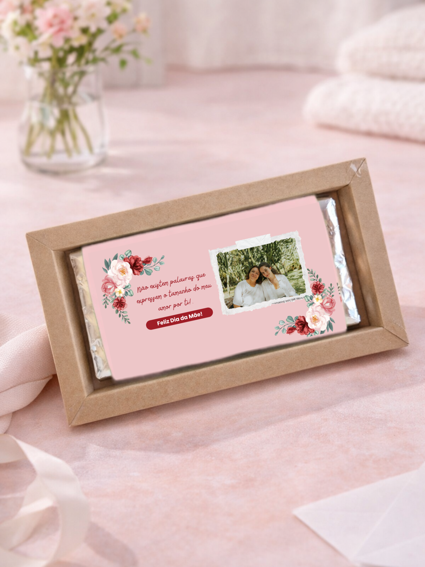 Barra de chocolate com rótulo rosa com flores e fotografia em embalagem de cartão castanho.