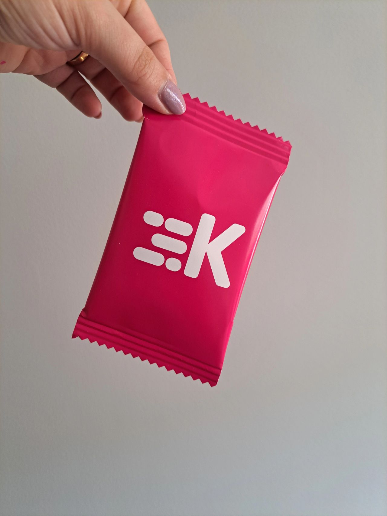 Pacote rosa com logotipo branco em mão sobre fundo cinzento