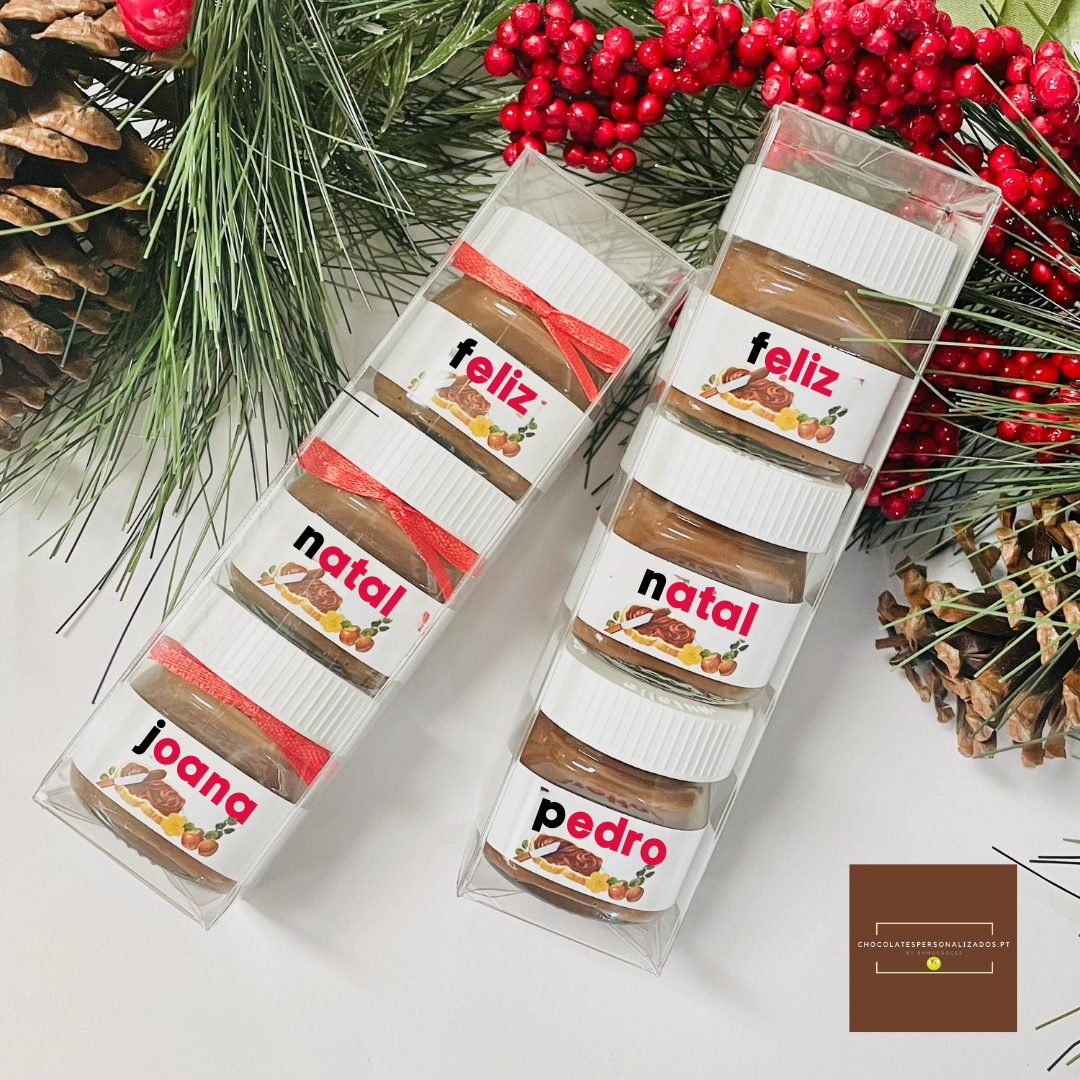 Frascos pequenos de creme castanho em caixas transparentes com rótulos festivos sobre fundo branco e decoração natalícia