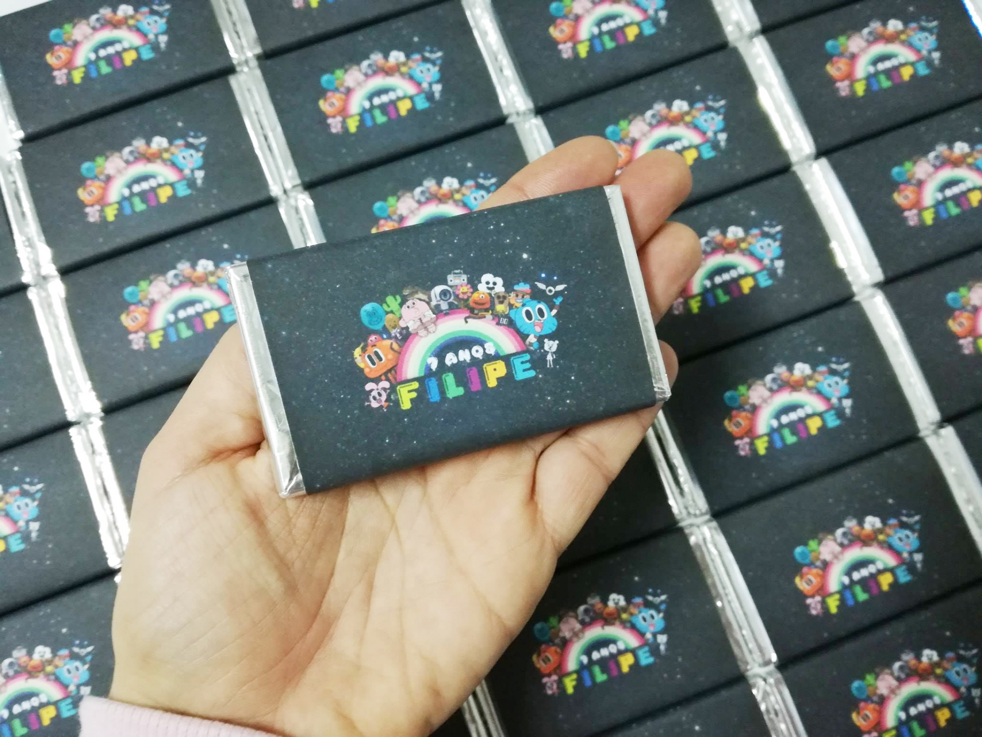 Caixa pequena retangular com design colorido e texto 'FILIPE 4 ANOS'