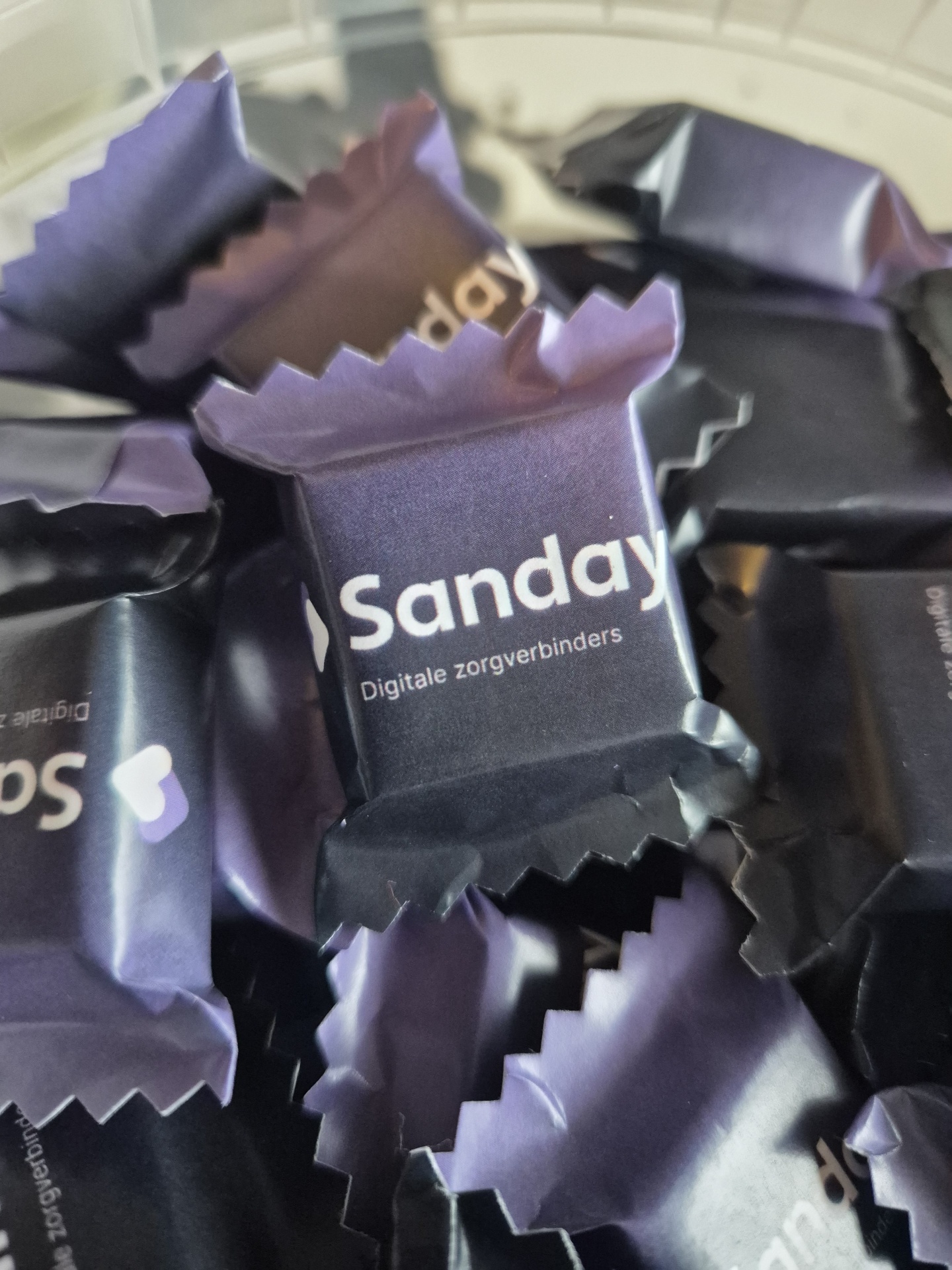 Doces embalados em papel roxo escuro com texto branco Sanday