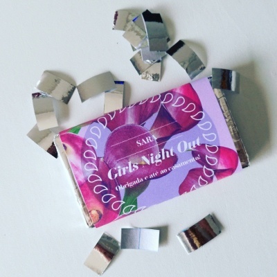 Embalagem de papel de chocolate roxa com texto e pedaços de papel prateado rasgados ao redor