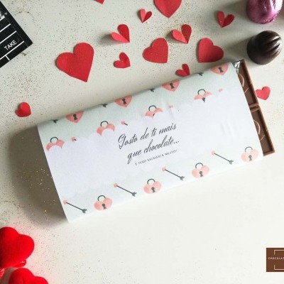 Barra de chocolate com embalagem floral e corações decorativos em fundo branco