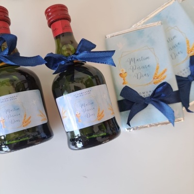 Mini garrafas e caixas azuis com laços azuis, rótulos com texto e decoração dourada.