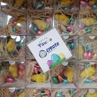 Caixas com chocolates em forma de pintainhos amarelos e ovos coloridos com cartão da Páscoa ao centro