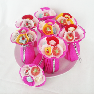 Pequenos bouquets decorativos com flores coloridas e figuras de pássaros em papel crepom rosa num prato branco