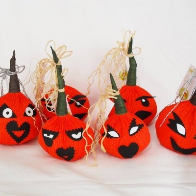 Seis abóboras decorativas de papel alaranjadas com expressões faciais e cordões para pendurar