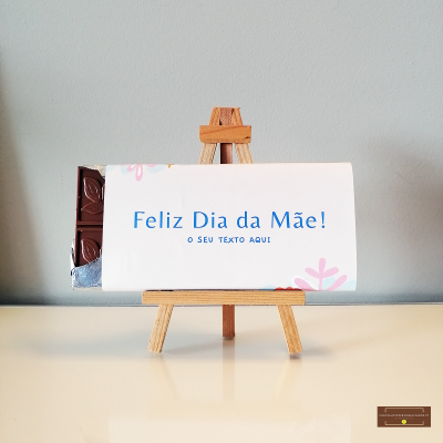 Barra de chocolate embrulhada com texto 'Feliz Dia da Mãe!' em cavalete de madeira