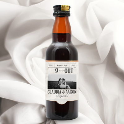 Garrafa pequena com etiqueta personalizada de casamento sobre tecido branco