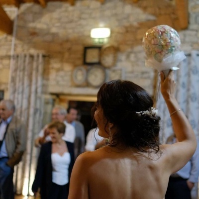 Mulher de costas com vestido sem alças segurando bouquet colorido em ambiente interior rústico