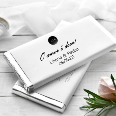 Barras de chocolate embrulhadas em papel branco com texto personalizado e flores ao lado