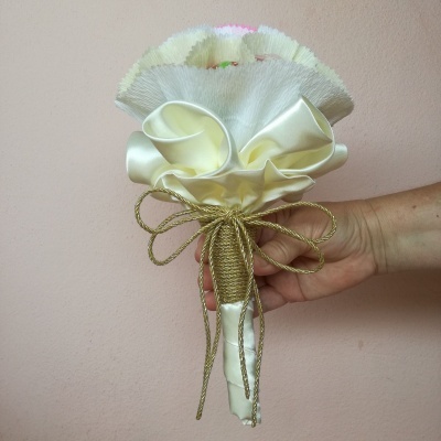 Pequeno bouquet em tons claros com fita dourada contra parede rosa