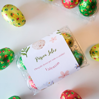 Ovos de chocolate coloridos em caixas plásticas com etiqueta branca de Páscoa