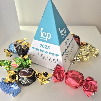 Calendário de mesa em pirâmide azul e branco com logótipo 'iep Grupo' 2025 rodeado por rebuçados coloridos
