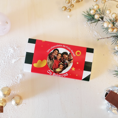 Caixa de chocolate com etiqueta vermelha e fotografia, decoração natalícia dourada e chocolate partido