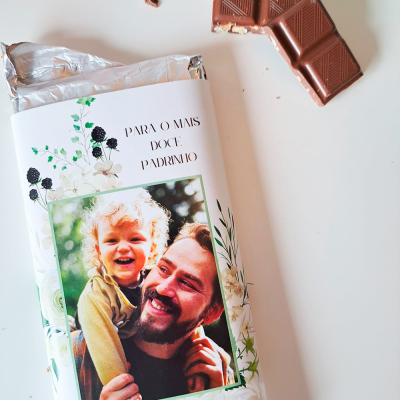 Barra de chocolate com foto e texto na embalagem, pedaços partidos ao lado