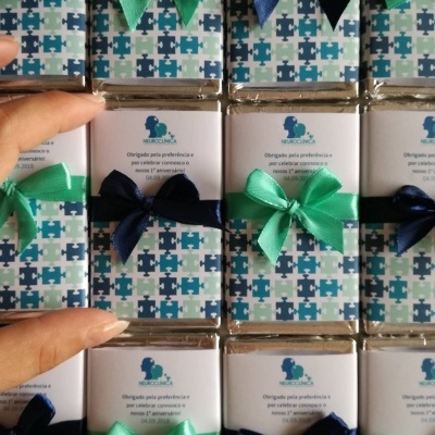 Barras de chocolate com papel decorado azul e verde, com laços e texto de agradecimento em português.