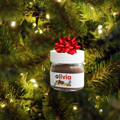 Pequeno frasco com tampa branca e laço vermelho pendurado numa árvore de Natal