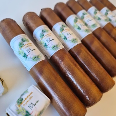 Tubos de couro castanho com etiquetas brancas e texto em português sobre superfície clara