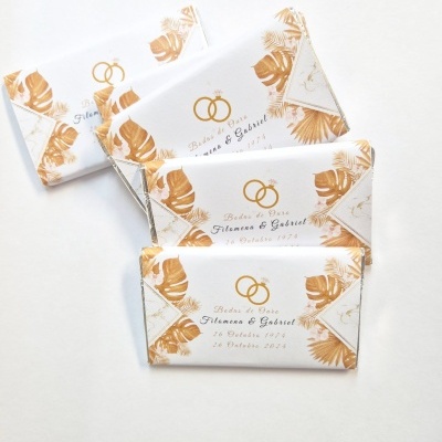 Barras de chocolate com embalagem branca decorada com folhas douradas e nomes de casamento