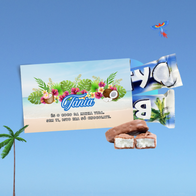 Dois tabletes de chocolate branco com coco, cartão com texto e fundo azul com coqueiro
