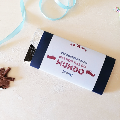 Barra de chocolate preto com embalagem dizendo 'MELHOR PAI DO MUNDO' sobre fundo branco