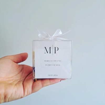 Caixa transparente com etiqueta branca e laço branco nas mãos