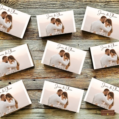 Caixas brancas com imagem de casal abraçado e texto João & Olívia sobre mesa de madeira