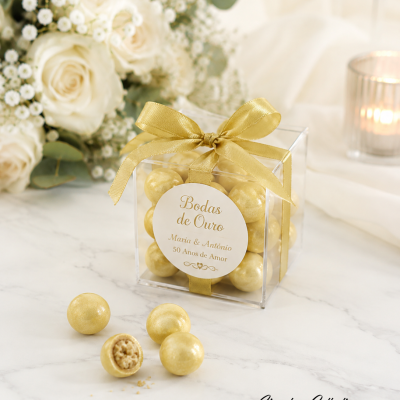Caixa transparente com bombons dourados e laço dourado, etiqueta com texto Bodas de Ouro Maria & António 50 Anos de Amor