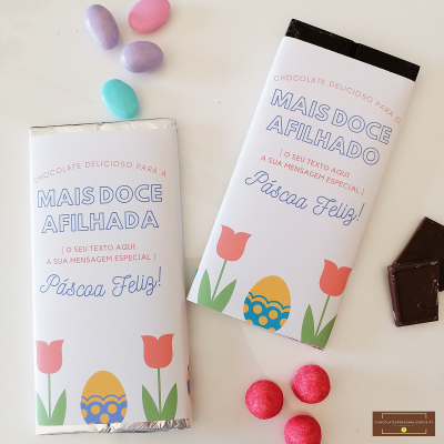 Barras de chocolate embrulhadas com texto de Páscoa e desenhos de flores e ovo, rodeadas por amêndoas coloridas e pedaços de chocolate