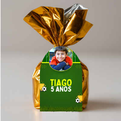 Embalagem dourada com etiqueta verde e foto de criança com texto 'TIAGO 5 ANOS'