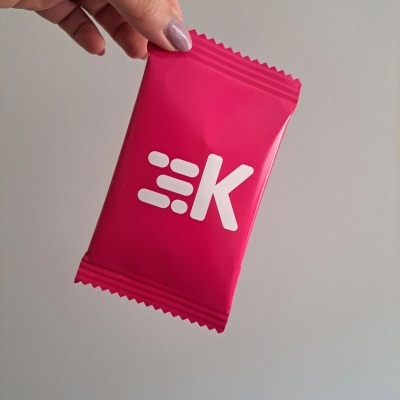 Sacos de Gomas com design personalizado para evento corporativo Pacote rosa com logotipo branco em mão sobre fundo cinzento