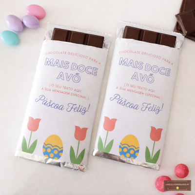 Duas barras de chocolate com embalagem decorativa de Páscoa para avós, rodeadas por ovos de chocolate coloridos.