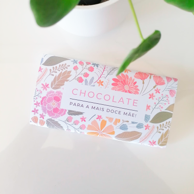 Barra de chocolate com embalagem floral e texto para a mãe sobre superfície branca