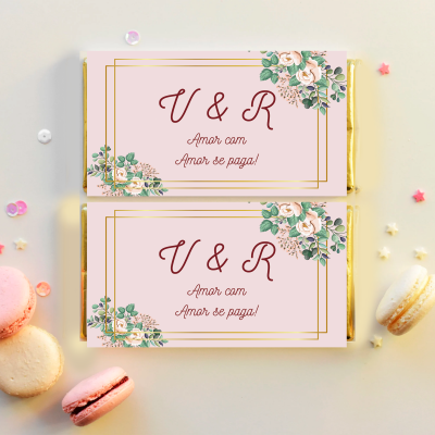Dois chocolates rosa decorados com flores e texto, cercados por macarons coloridos.