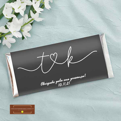 Barra de chocolate com embalagem preta e texto branco num tecido azul claro com flores brancas