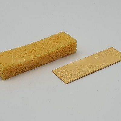 Esponja amarela e pedaço reto bege em fundo cinzento.