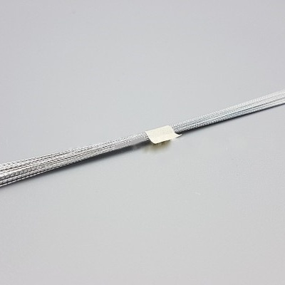 Cabo de aço prateado fino com etiqueta branca numa superfície cinza