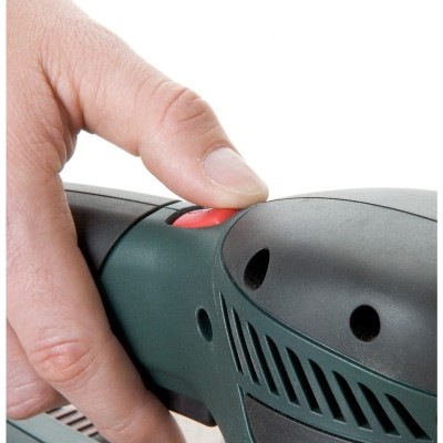 Pessoa segurando ferramenta elétrica preta e verde com botão vermelho