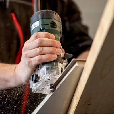 Ferramenta elétrica de carpintaria a trabalhar numa peça de madeira clara