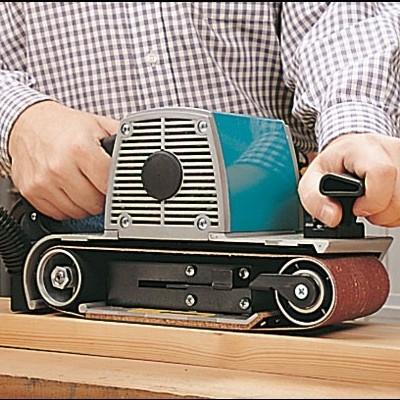 Lixador de cinta azul e preto com correia abrasiva castanha, mãos segurando, superfície madeira