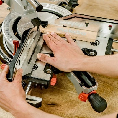 serra de corte de esquadria com peça de madeira e mão ajustando