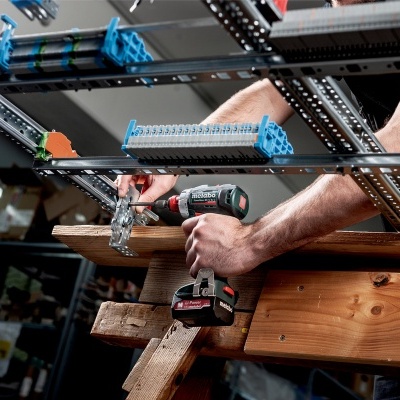 Homem a usar furadeira elétrica numa estrutura metálica numa oficina